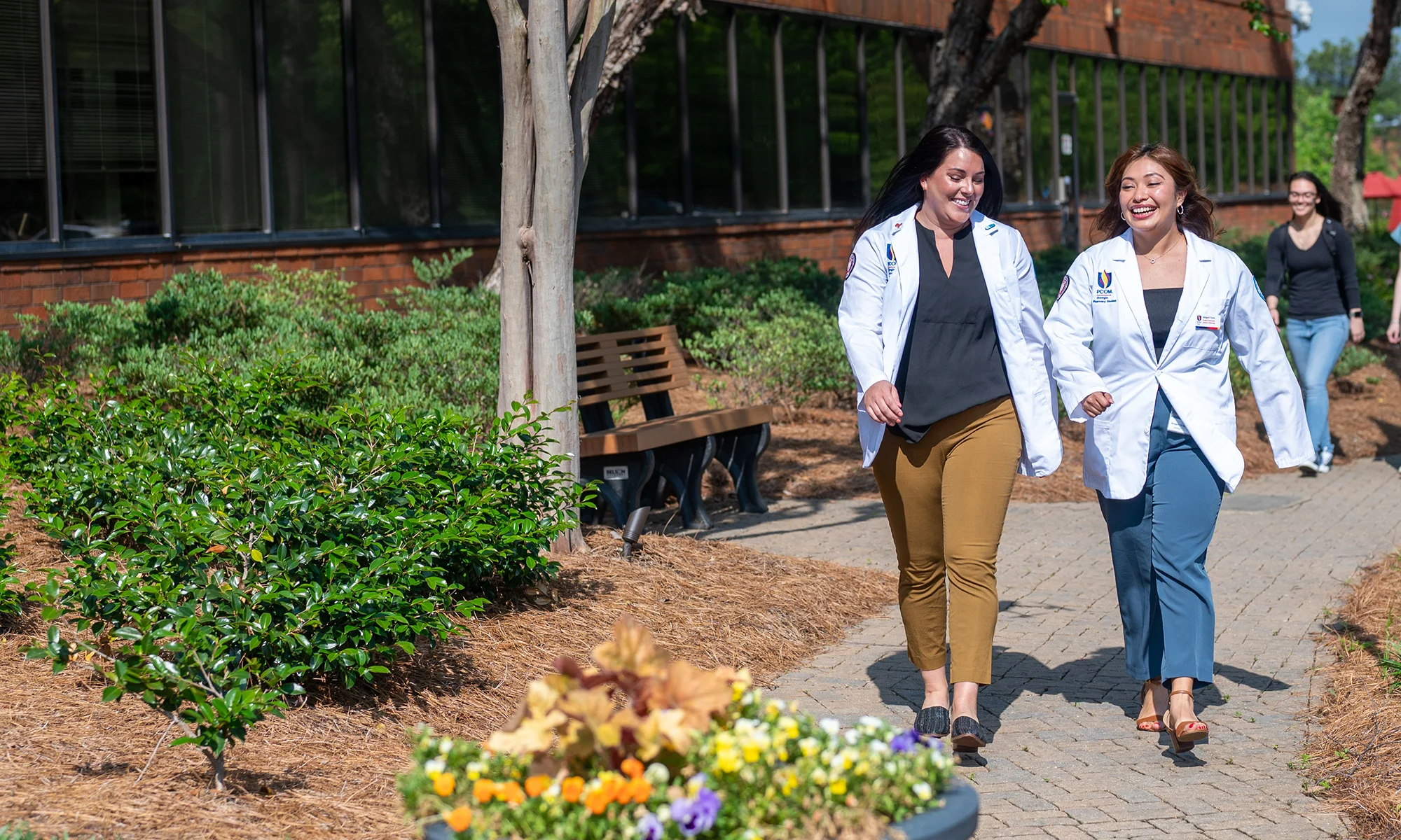Two PCOM Georgia medical students smiling while walking on an outdoor path