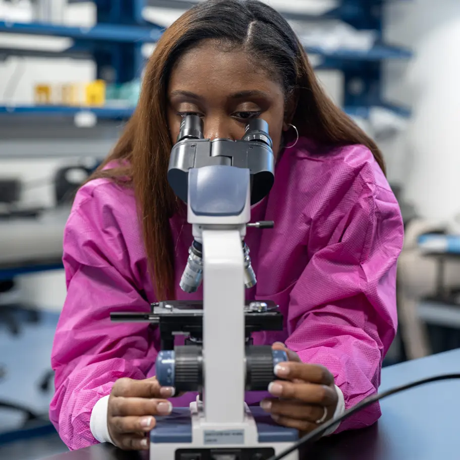 Evanné Casimir, a student in PCOM Georgia's MS in Medical Laboratory Science program, uses a microscope in a research lab