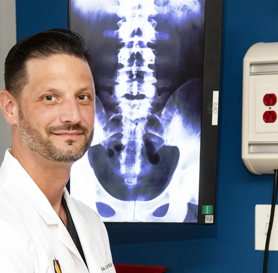 Erik Polan, DO ‘07, FACOI, in front of digital x-ray image