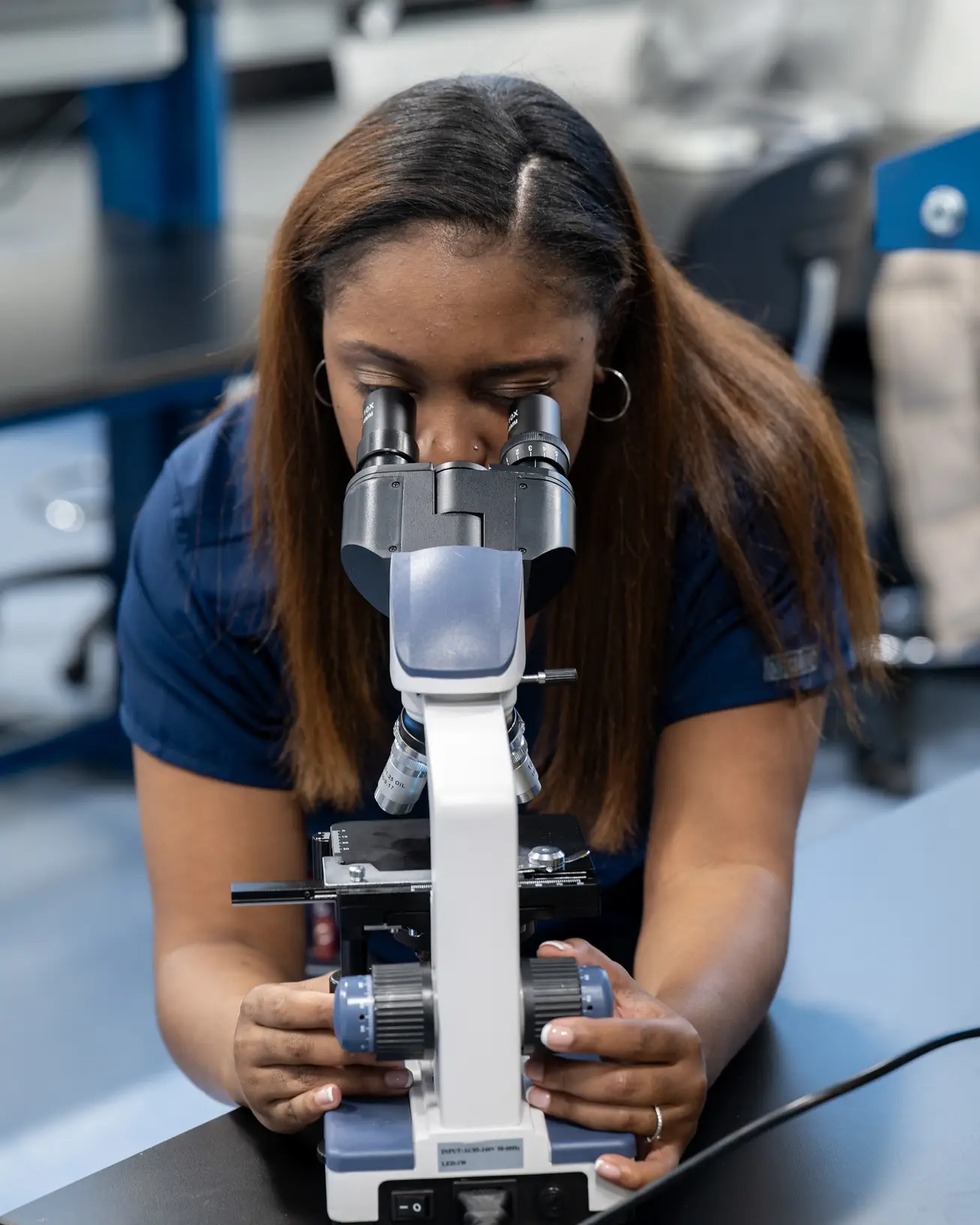 A medical laboratory science student looks into a microscope.