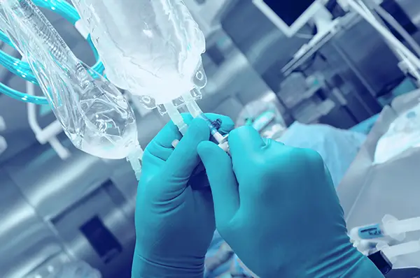 An infusion pharmacist adjusts an IV drip.