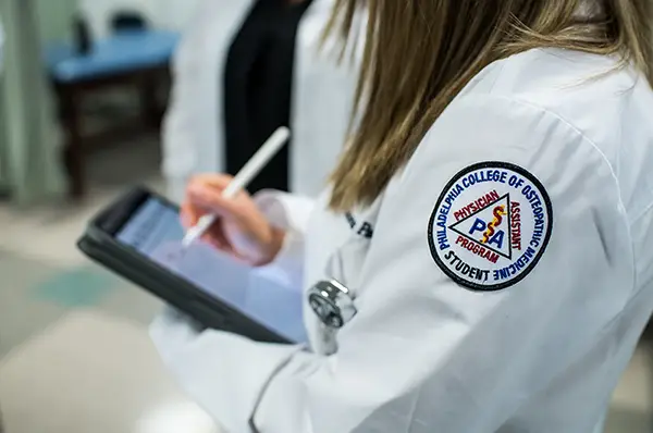 A physician assistant studies student makes notes on a tablet.