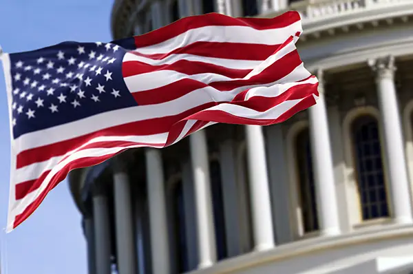 The United States flag flying in front of the U.S. Capitol Building.