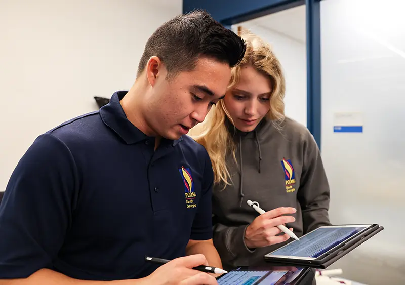 A peer mentor helps a fellow student with their FAFSA application on a notebook tablet