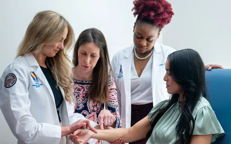 Rebekah Thomas, PharmD, PA-C, BCPS, BC-ADM, chair and program director, physician assistant studies, demonstrates the intricacies of a physical exam to PCOM Georgia physician assistant studies students, emphasizing hands-on learning and patient-centered care.