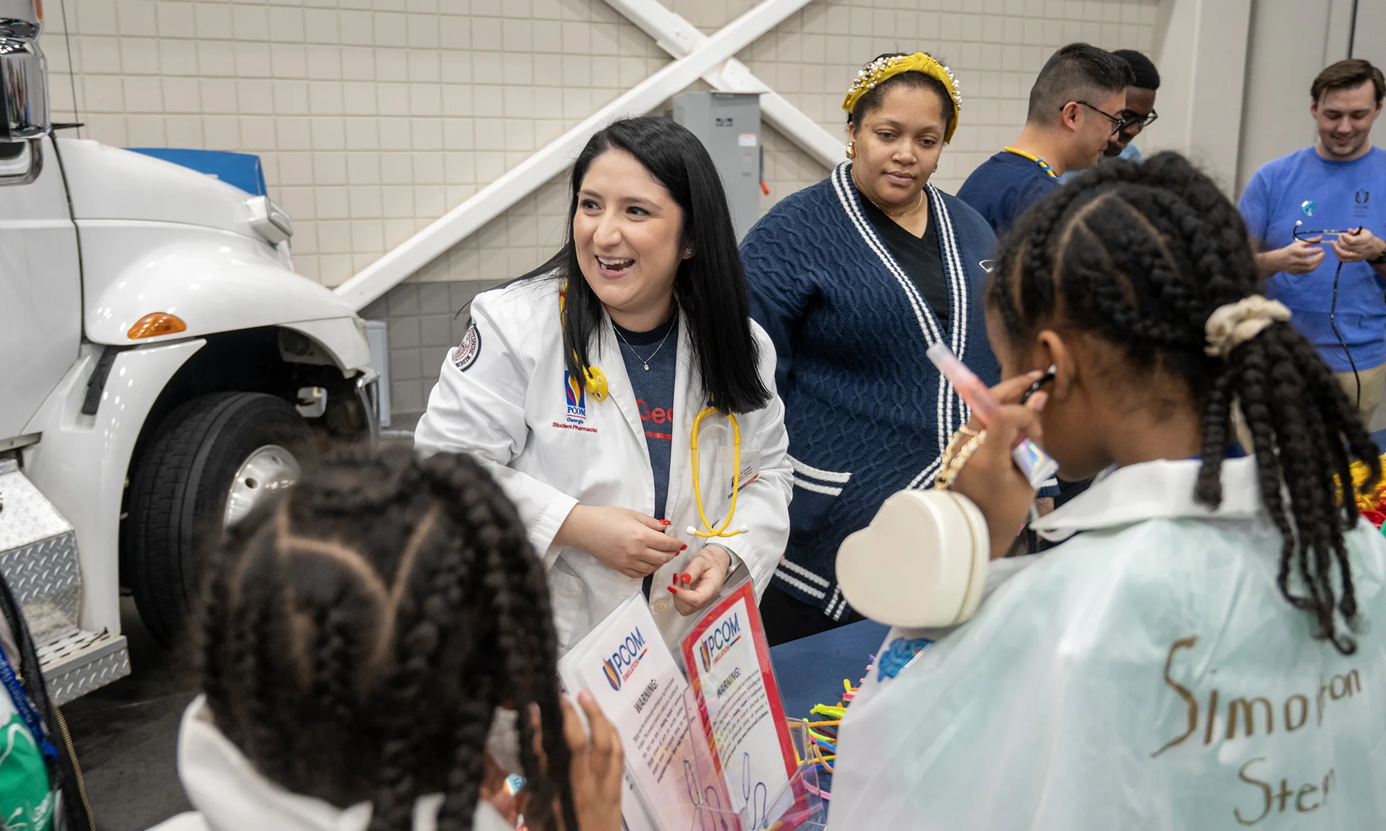 A PCOM Georgia medical student smiling while interacting with children at an annual science fair community event