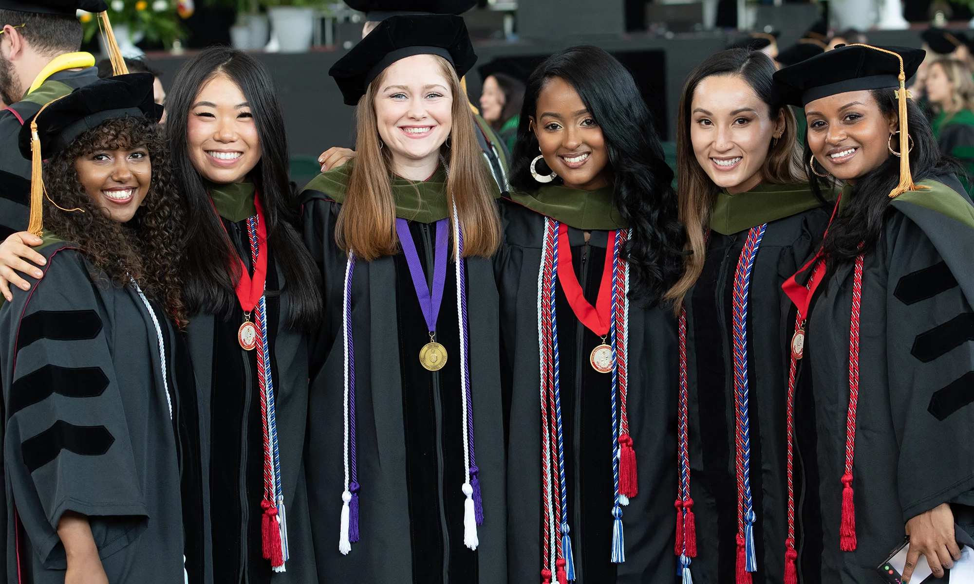 PCOM PharmD students smiling in their caps, gowns and regalia during a commencement ceremony