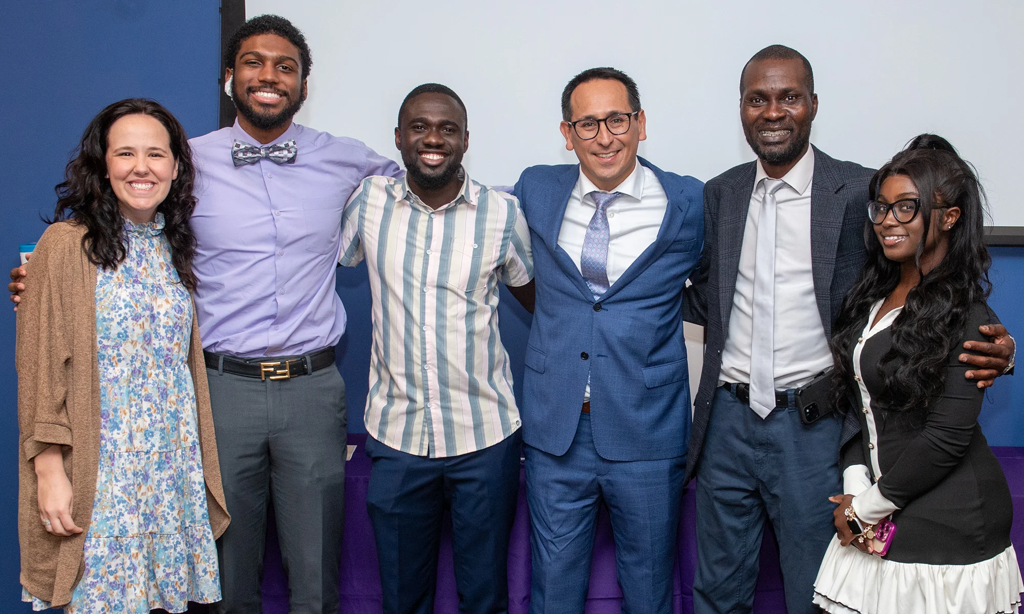 A group of PCOM students and faculty members smiling during an honors society induction ceremony