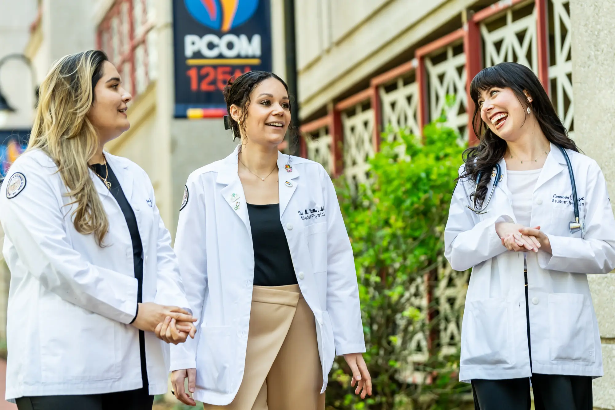 Three PCOM med students walking and smiling on a path on the Philadelphia campus