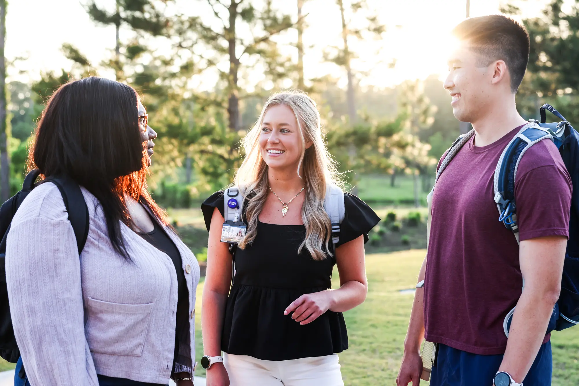 Three graduate students smiling and talking outside with a bright sunset in the background at PCOM South Georgia