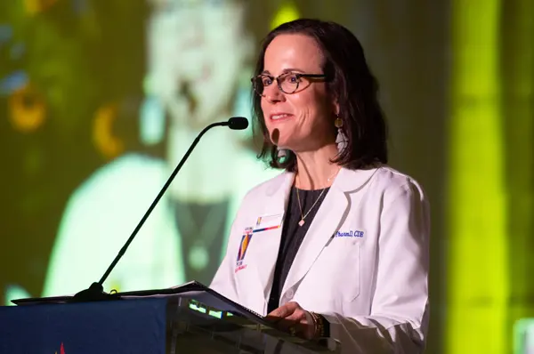 Dr. Reece stands at a podium to deliver remarks at a PharmD white coat ceremony at PCOM Georgia