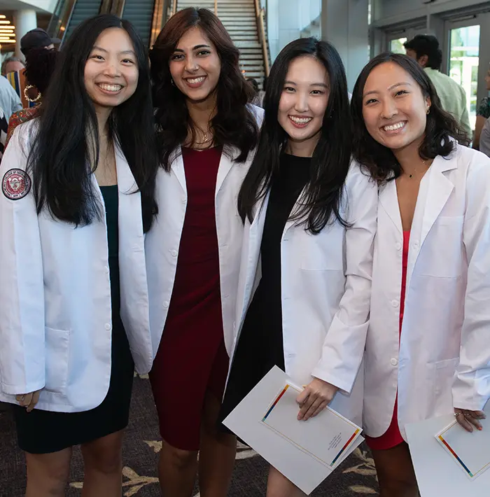 Students stand side-by-side in their white coats