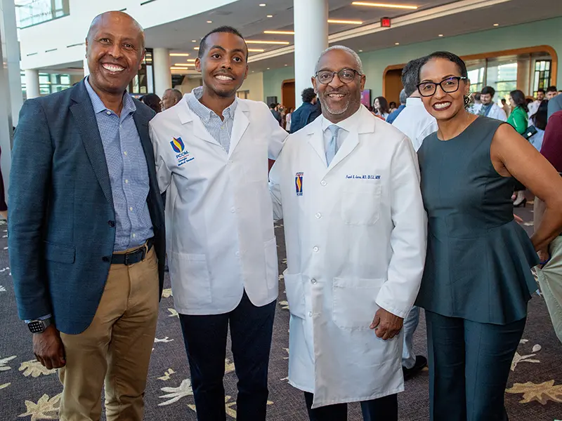 A student and his family pose with a PCOM professor