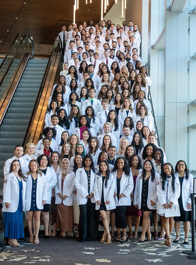 Students pose on staircase wearing white coats