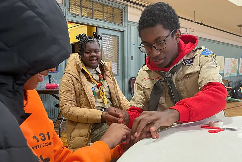 Boy scouts smile as they complete a hands-on first aid learning exercise alongside PCOM student volunteers