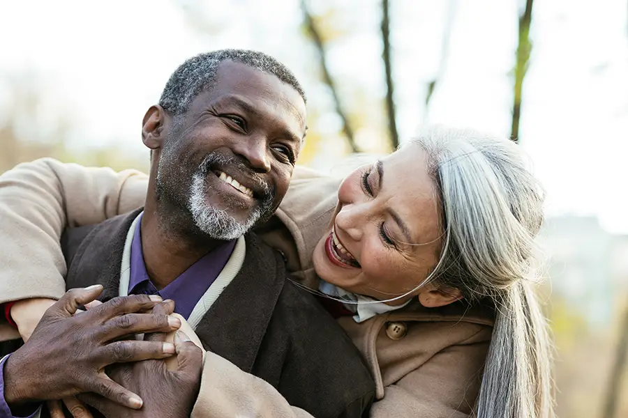 Two seniors smile as they embrace outside during the early winter months