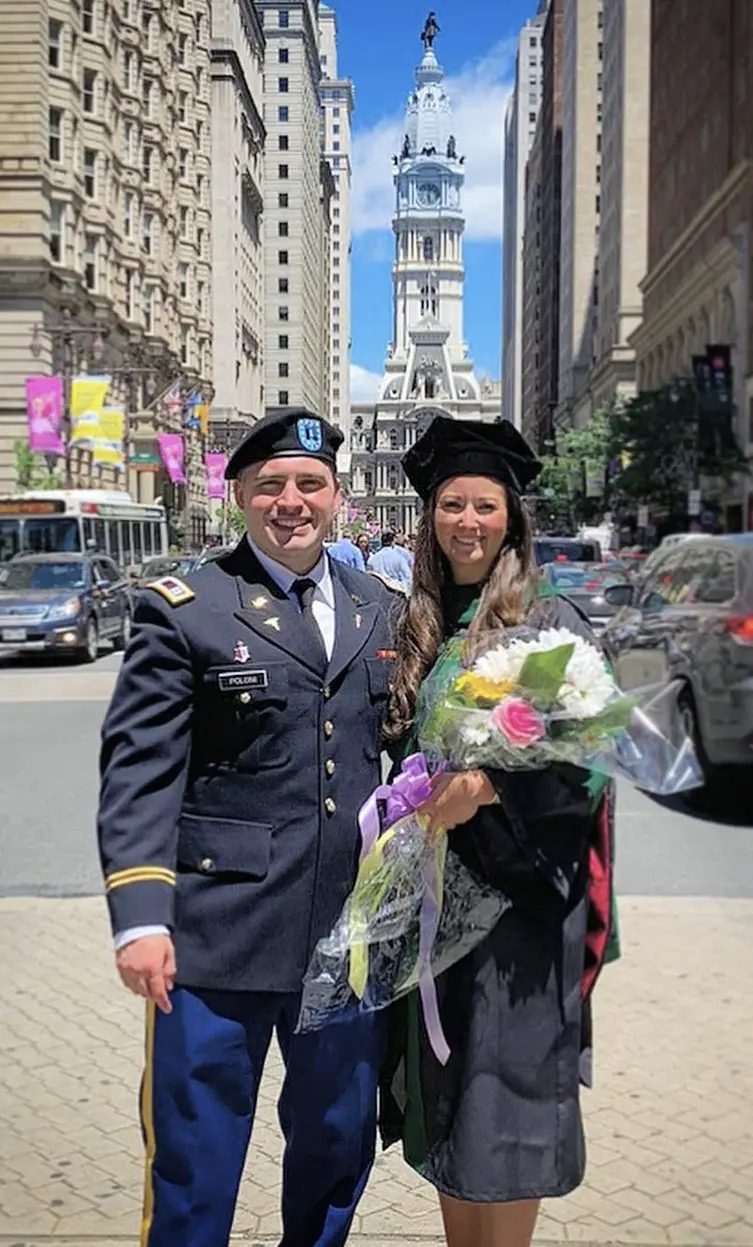 PCOM chief surgery resident Christina Monaco Poloni, DO '19, and her spouse smile in their regalia on Philadelphia's Broad Street.