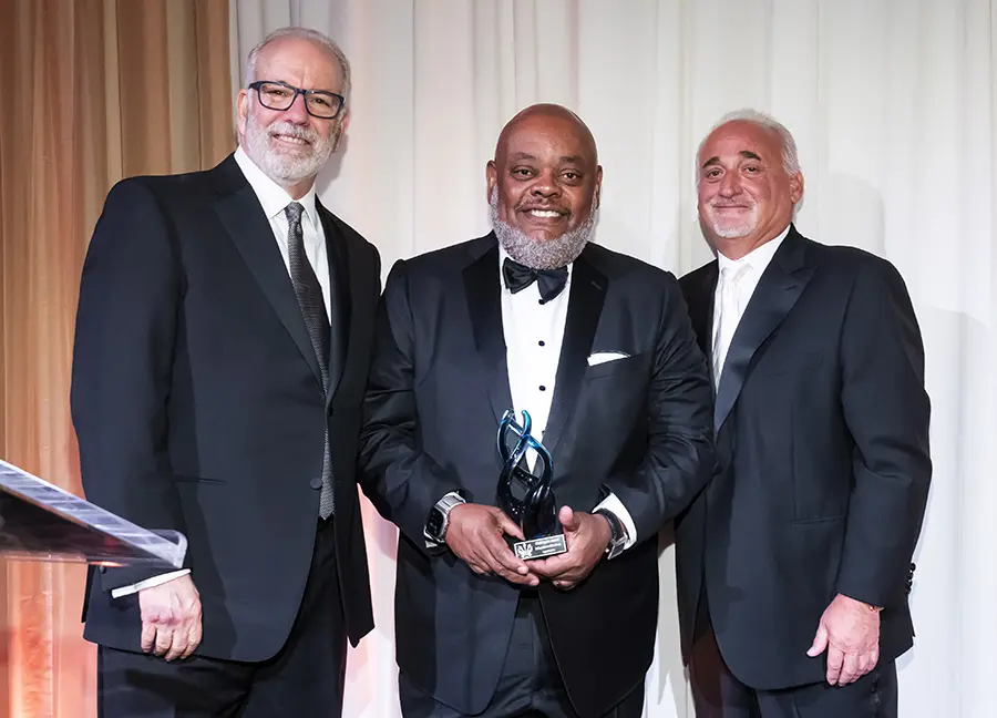 PCOM President Jay Feldstein, DO '81; IBX CEO Gregory Deavens; PCOM Chairman of the Board of Trustees Thomas Gravina smile on stage during the PCOM awards event