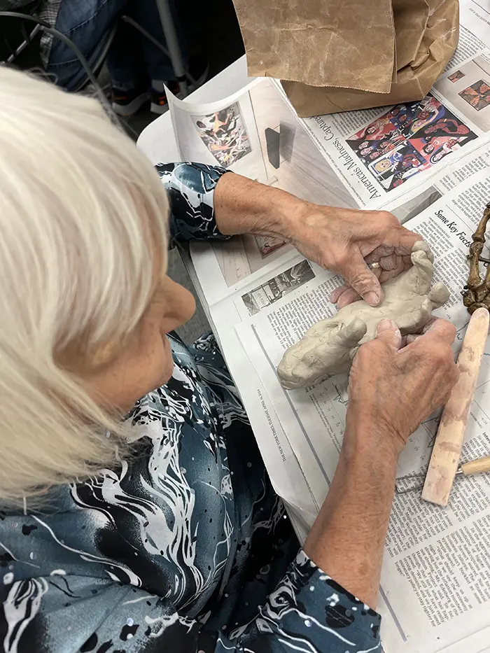 Art student Betsy Clayton sculpts a human hand with clay over a newspaper workspace