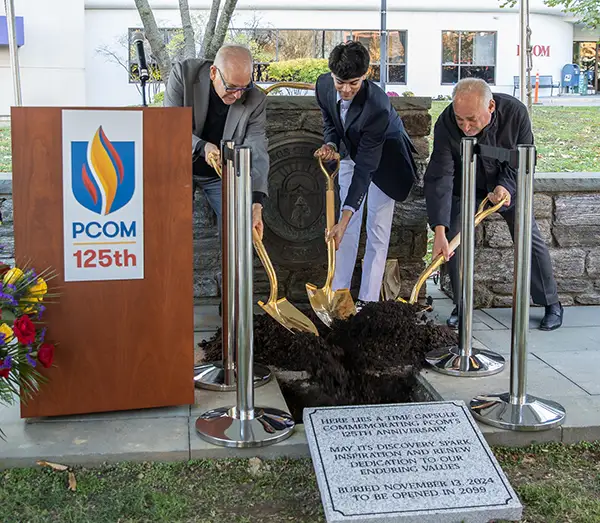 Jay S. Feldstein, DO ’81, Krish Kondisetti (DO ’27), and Thomas Gravina hold golden shovels during time capsule ceremony