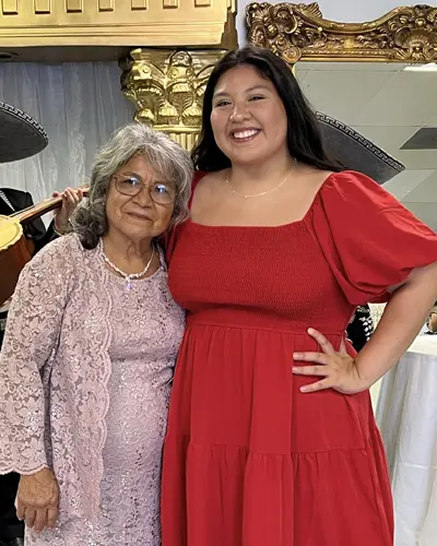 PCOM's Kimberly Lopez smiles in a red dress alongside her grandmother.