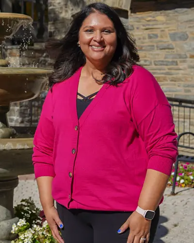 PCOM's Maricela Montijo-Davis smiles as she stands outside in the donor garden on the Philadelphia campus