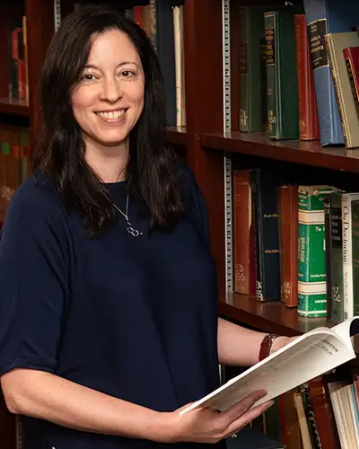 Michelle Lent, PhD, poses in library holding open book