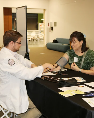 DO student takes blood pressure reading from female patient.