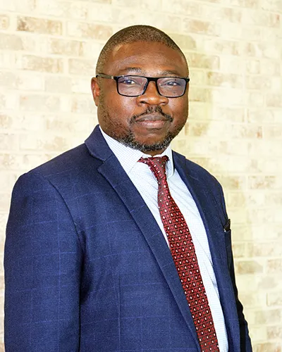 Headshot photo of PCOM professor Joshua Owolabi, PhD, FAcadMEd wearing a suit and tie