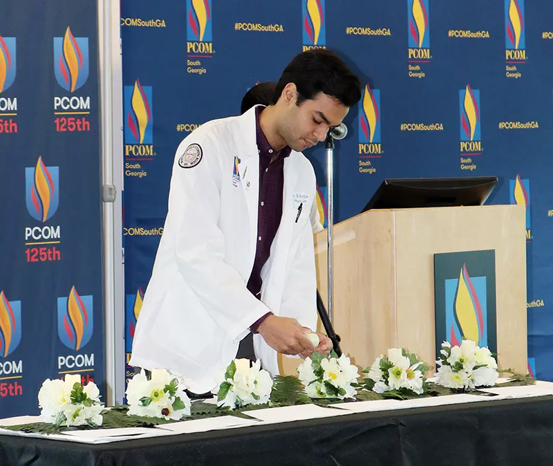 A PCOM South Georgia DO student lights a candle during the body donor memorial service.