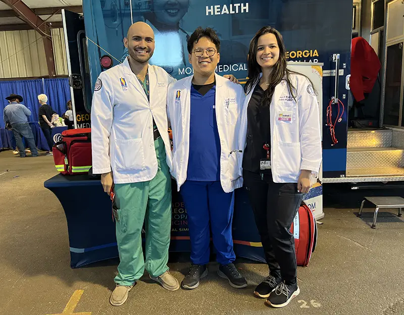 PCOM South Georgia medical students smile in front of the College's informational booth at the Sunbelt Ag Expo