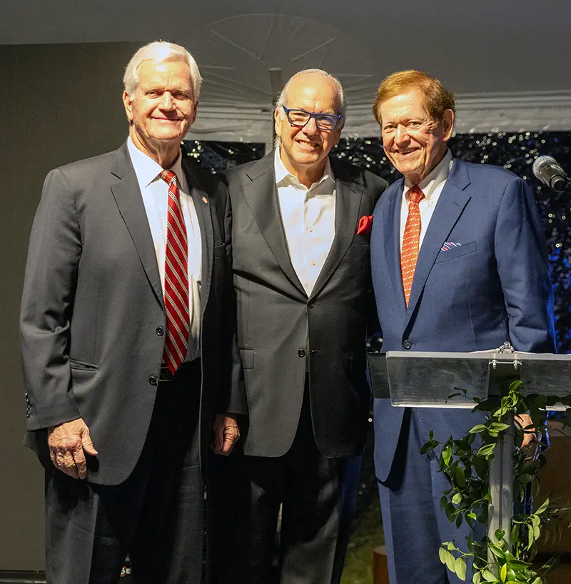 PCOM President and CEO Dr. Feldstein smiles on stage with Moultrie businessmen Dan Jeter and Jimmy Jeter of Jeter Partners LLC.