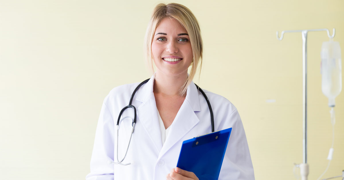 Female physician assistant students smiles while holding a clipboard