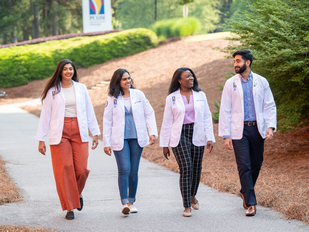 DO students walking in white coats outside