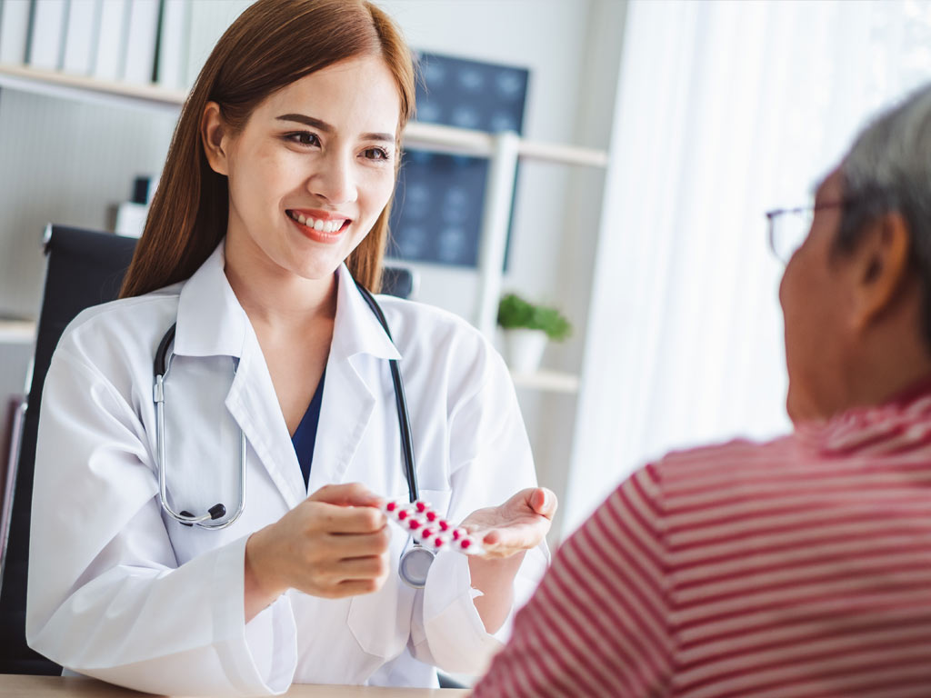 Pharmacist hands medication to patient across desk