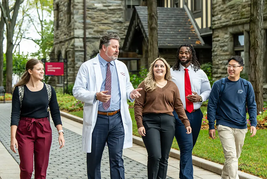 PCOM students walking with Dr. Bidey in front of the Levin Administration Building on the Philadelphia campus.