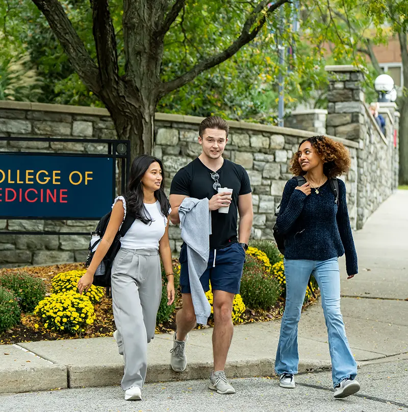 PCOM students smiling and walking on a sidewalk during a campus tour at the Philadelphia campus.