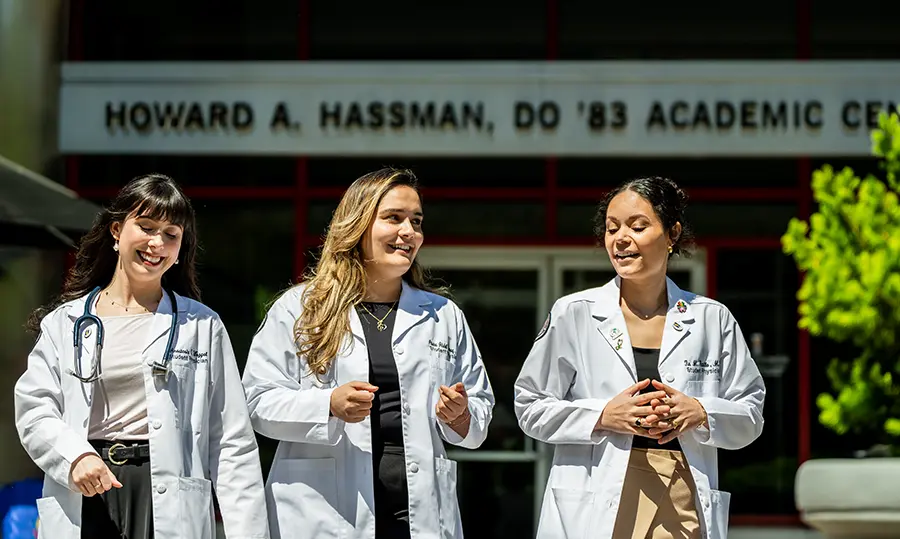 PCOM students in white coats talking in front of the Hassman Academic Center on the Philadelphia campus.