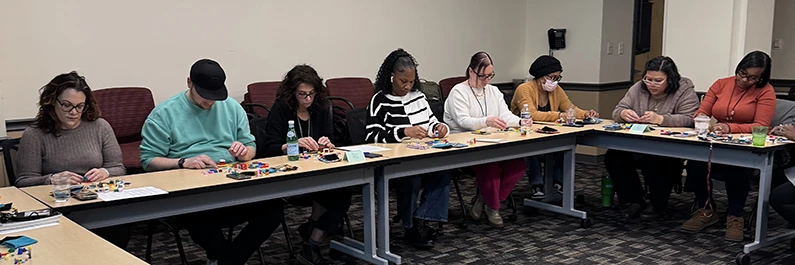 Community Behavioral Health staff members build with LEGO bricks on a table during Glassman's workshop