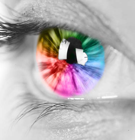 Black and white macro photograph of human eye, but the iris is colored in a rainbow spectrum.