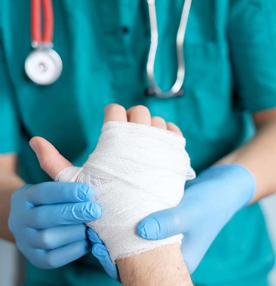 Macro shot of patient's hand being bandaged by a nurse.