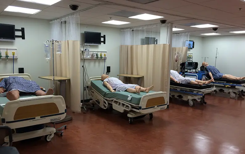 Emergency medicine simulation area featuring hospital beds, high fidelity mannequins and monitoring equipment in PCOM Georgia's sim center